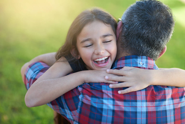 Μπαμπάδες στο σπίτι. Ένα χαρούμενο κοριτσάκι που αγκάλιαζε τον πατέρα της στο σπίτι.. - Φωτογραφία, εικόνα