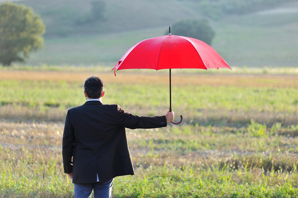insurance and protection concept, businessman with umbrella in the field - Photo, Image