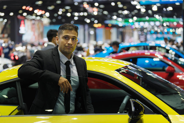 portrait of caucasian businessman in motor show or car showroom looking for new car to buy - Zdjęcie, obraz