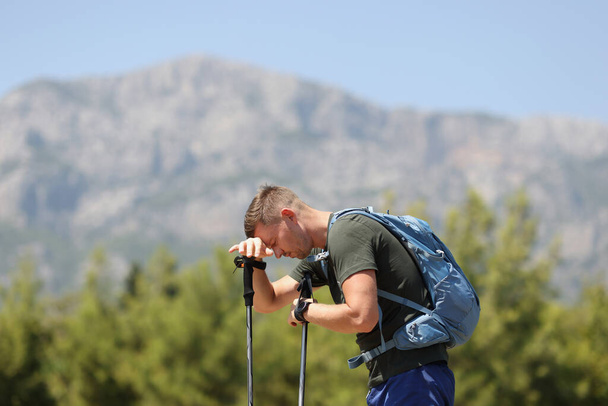 Tired man with Scandinavian walking sticks on mountain - Photo, Image