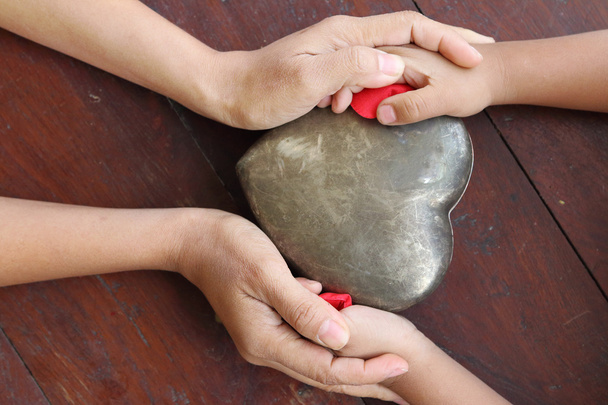 Kırmızı ve metal kalp şeklinde holding kadın ve çocuk eller. - Fotoğraf, Görsel