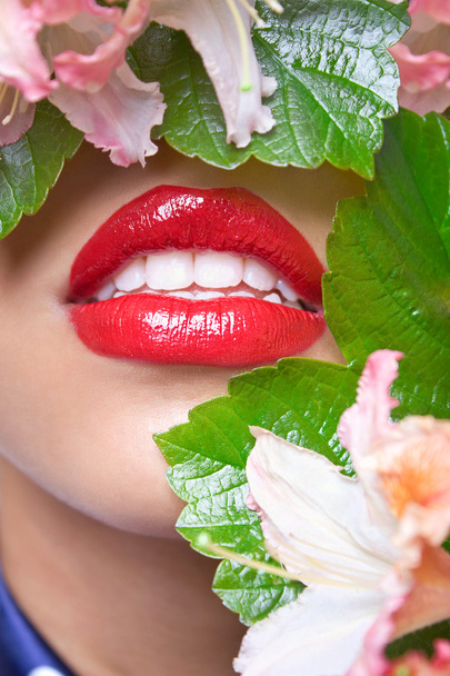 Closeup of a woman's face covered with green leaves and flowers - Photo, Image
