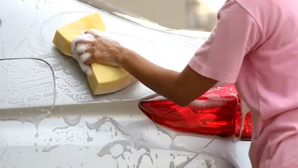 Vrouw wassen een zilveren auto met een gele spons. - Video