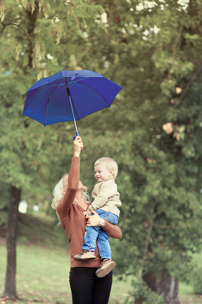 Mother and baby with umbrella walking in autumn day, soft vintag - Foto, Imagem