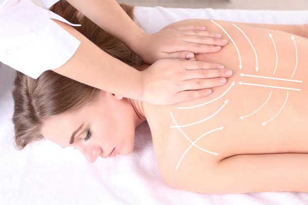 Massaggio alla schiena. Bella giovane donna con massaggio alla schiena nel salone spa (con le frecce
) - Foto, immagini