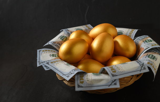 Goldene Eier und Dollar in einem Korb auf schwarzem Hintergrund, - Foto, Bild