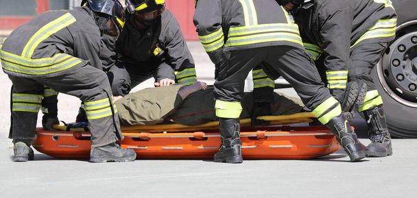 τέσσερις πυροσβέστες και ένα τραυματισμένο άτομο στο φορείο - Φωτογραφία, εικόνα