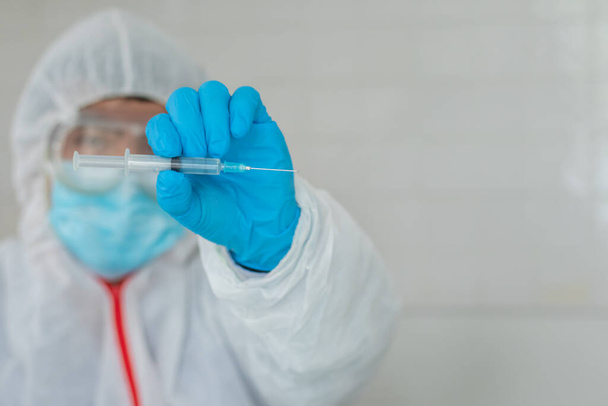 El equipo médico usó un traje protector contra el coronavirus y guantes de goma para examinar una muestra de tubos biológicos contaminados por el virus Corona Covid 19 e investigar una vacuna para prevenir Covid. - Foto, imagen