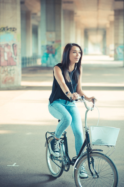 молода красива брюнетка пряме волосся жінка використовує велосипед і посміхається
 - Фото, зображення