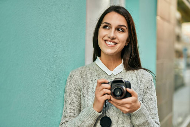 Fiatal spanyol nő mosolyog boldog segítségével kamera a városban. - Fotó, kép
