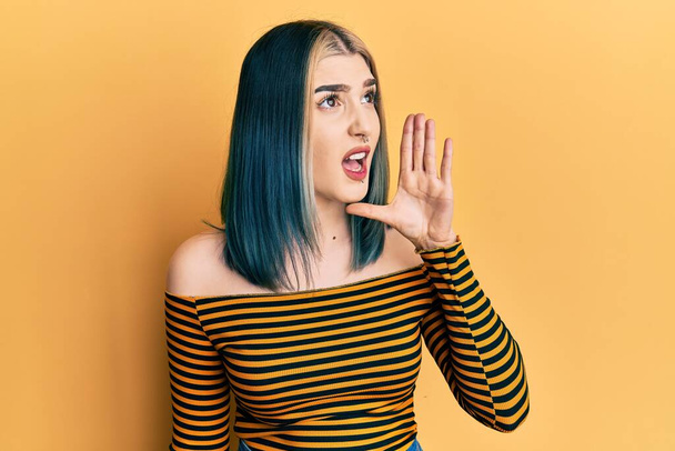 Young modern girl wearing casual striped shirt shouting and screaming loud to side with hand on mouth. communication concept.  - Photo, Image