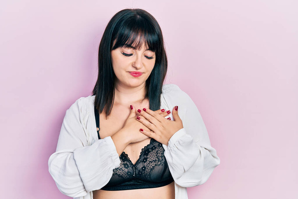 Young hispanic woman wearing lingerie smiling with hands on chest with closed eyes and grateful gesture on face. health concept.  - Фото, изображение