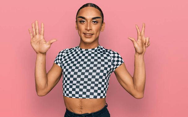 Hispanic transgender man wearing make up and long hair wearing modern clothes showing and pointing up with fingers number eight while smiling confident and happy.  - Zdjęcie, obraz