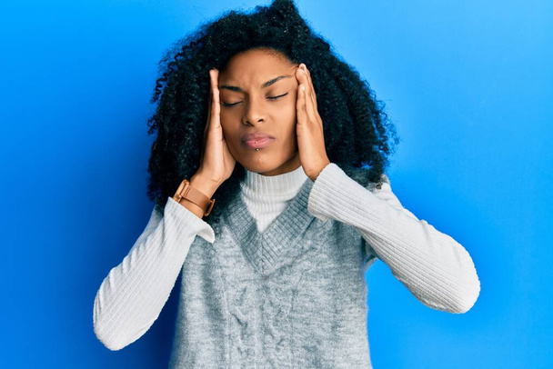 Afroamerikanerin mit Afro-Haaren in lässigem Winterpullover mit Hand auf dem Kopf, Kopfschmerzen wegen Stress. Migräne.  - Foto, Bild