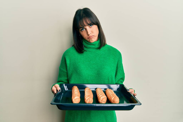 Young hispanic woman holding homemade bread depressed and worry for distress, crying angry and afraid. sad expression.  - Photo, Image