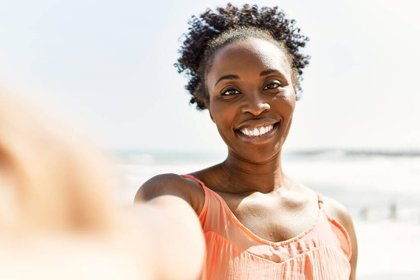 若いアフリカ系アメリカ人女性の笑顔幸せな夏の日にビーチで自画撮り写真を撮る - 写真・画像