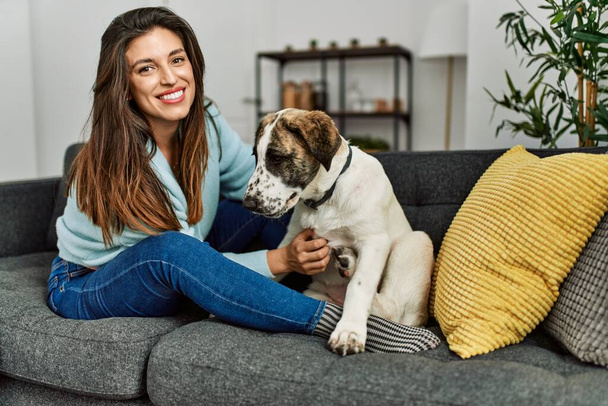 Giovane donna che abbraccia cane seduto sul divano a casa - Foto, immagini
