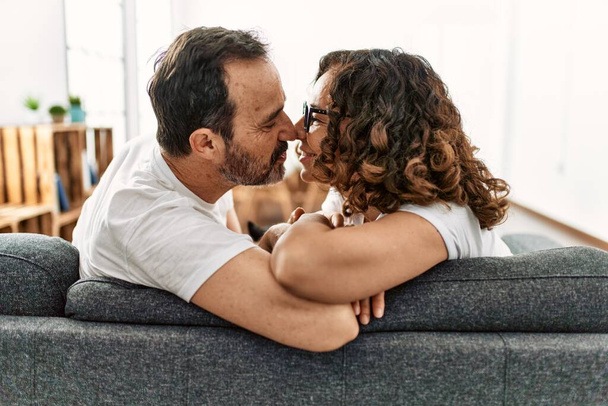 Střední věk hispánský pár usměvavý šťastný sedí na pohovce doma. - Fotografie, Obrázek