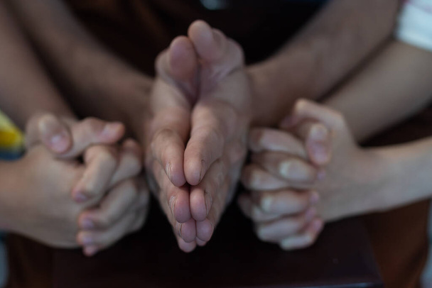 Dva křesťané se modlí za mladé muže přátele na dřevěném stole v kostelní modlitebně, aby ho povzbudili a podpořili v jeho problému a duchovním růstu, malé modlitební skupiny a konceptu společenství. - Fotografie, Obrázek