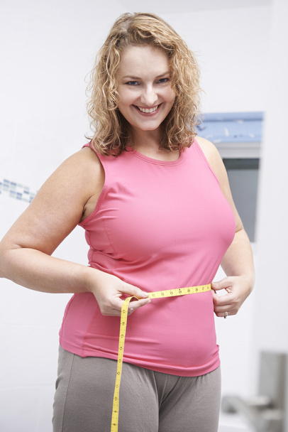Happy Plus Size Woman Measuring Waist In Bathroom - Photo, image