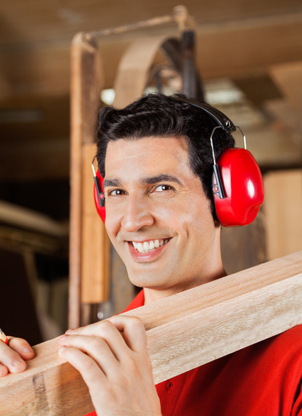 Happy Carpenter Carrying Wooden Plank On Shoulder - Foto, immagini