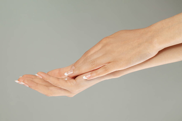 Manicure dłoni z francuskim manicure na szarym tle. Manicure i opieka zdrowotna - Zdjęcie, obraz