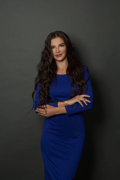 Happy attractive woman with arms crossed. Fashion model with long hair in blue dress - Zdjęcie, obraz