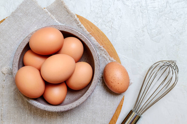 Свежие коричневые куриные яйца в миске. Вид сверху. Концепция завтраков, выпечки, сельскохозяйственных экологически чистых продуктов. - Фото, изображение