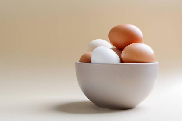 Different farm eggs in a bowl on a pastel background. Healthy food concept, organic food - Photo, Image