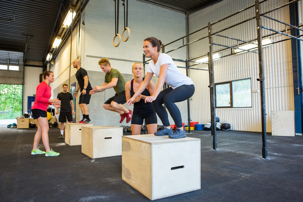 Athletes Doing Box Jumps At Gym - Фото, изображение