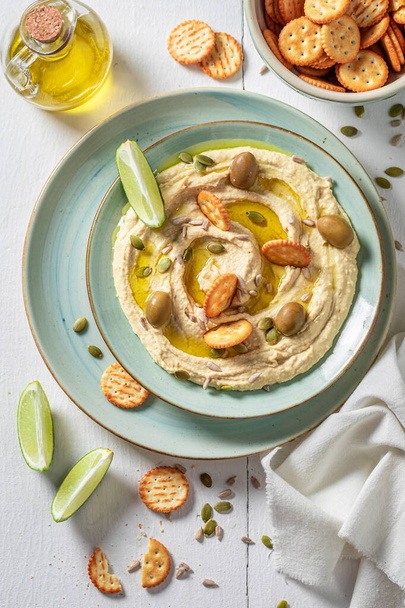 Yummy and fresh hummus with round crackers and olives. Delicious and vegan hummus with olive and limes. - Valokuva, kuva