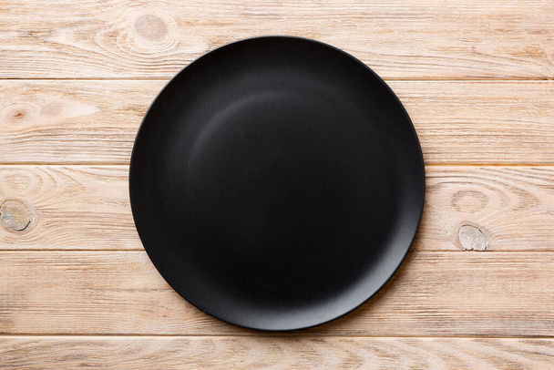 Top view of black plate on wooden background. Empty space for your design. - Foto, Imagem