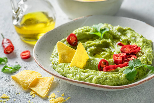 Tasty and homemade guacamole with nachos, herbs and peppers. Nachos with guacamole as mexican snack. - Фото, зображення