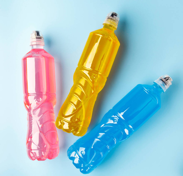 Μπουκαλάκια πλαστικά με χρωματιστό υγρό. Χρωματιστά μπουκάλια αθλητικής διατροφής, ισοτονικά. - Φωτογραφία, εικόνα