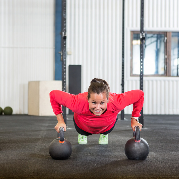 Woman Doing Pushup Exercise With Kettlebell - Photo, image