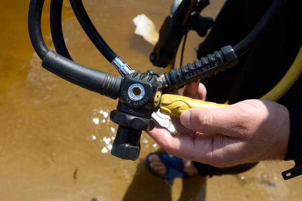 Mains de plongeur tenant un réducteur de pression d'air - partie d'un équipement de plongée - Photo, image