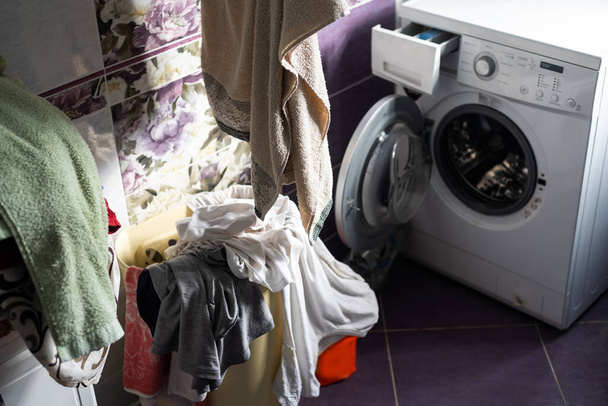 洗濯機の横にある家の洗濯室のインテリアは、汚れた服のためのバスケットを立って物事で満たされた分離する - 写真・画像