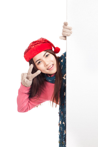 Asian girl with red christmas hat peeking from behind blank bann - Foto, Imagem