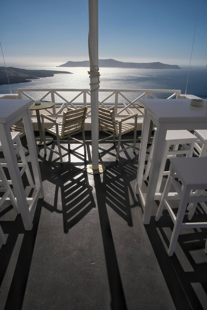Захватывающий дух вид из открытого бара со стульями и столами в Fira Santorini - Фото, изображение