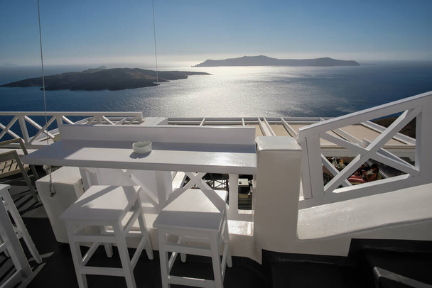 Atemberaubender Blick von einer Außenbar mit Stühlen und Tischen in Fira Santorini - Foto, Bild