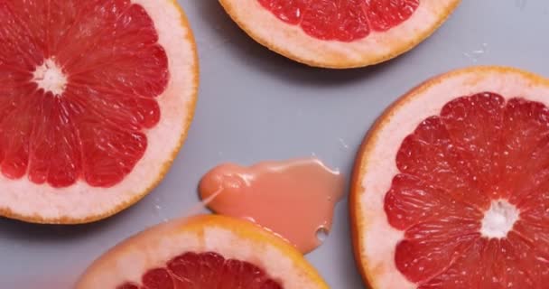 Top view rotation of fresh slice of grapefruits juice and gel serum , organic cosmetics, vitamin C, fresh citrus fruits, grapefruit extract - Footage, Video