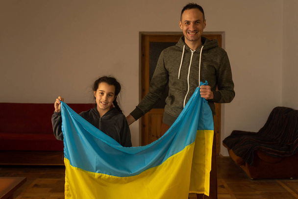 family with one child looking at camera and Ukrainian flag - Photo, Image