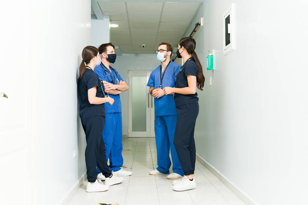 Ärzteteam. Vier Ärzte und Chirurgen diskutieren im Krankenhausgang über einen kranken Patienten  - Foto, Bild