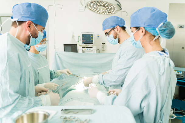 Chirurgové, lékaři a zdravotní sestry pracující na pohotovostní operaci v nemocnici - Fotografie, Obrázek