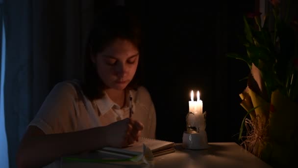 the girl writes something at night by the light of a candle, reads what is written, blows out the candle. inspiration concept, creativity at night. Theme of magic and mystical rituals. - Materiał filmowy, wideo