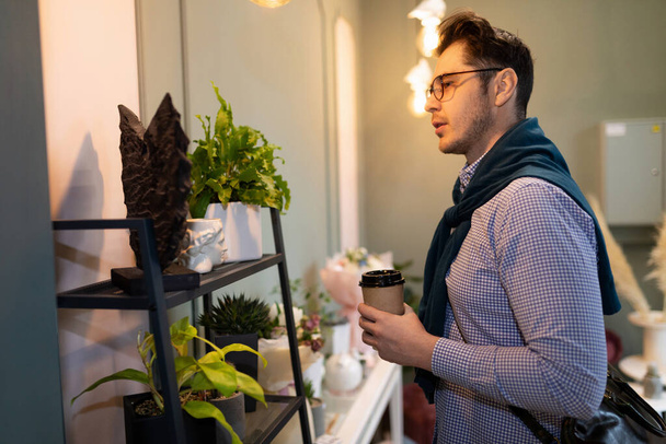 чоловік вибирає квітковий горщик в інтер'єрі квіткового магазину - Фото, зображення