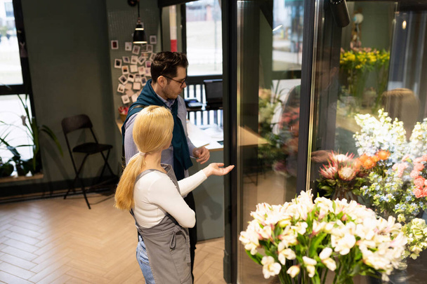 продавець і покупець в квітковому магазині визначаються набором квітів для букета - Фото, зображення