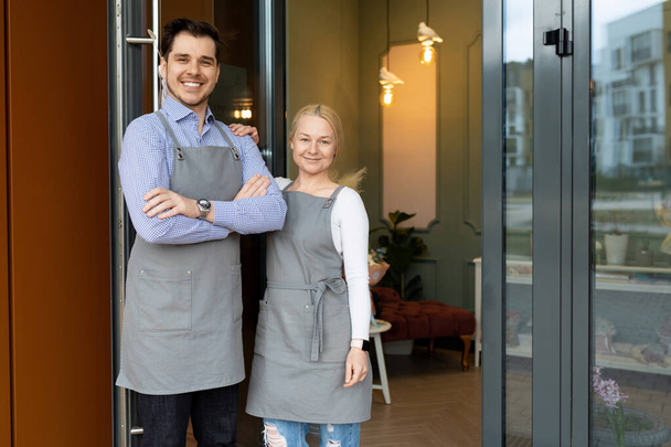 proprietari di piccole imprese sono felici di accogliere i loro clienti alla porta del loro negozio o ristorante - Foto, immagini