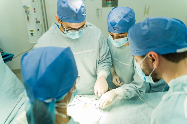 Hoge hoek van een team chirurgen die een operatie uitvoeren op een patiënt in het ziekenhuis - Foto, afbeelding