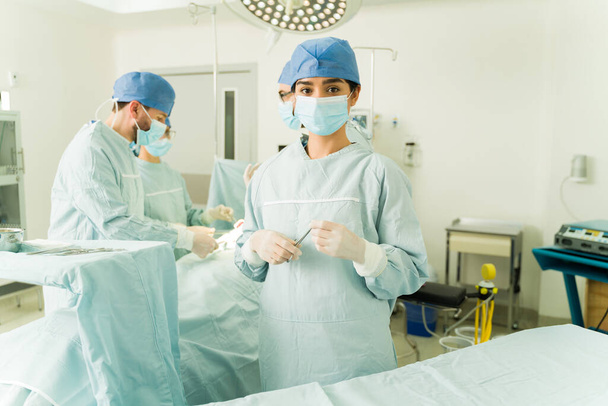 Medical nurse looking at the camera while holding surgery instruments at the operating room - Photo, Image